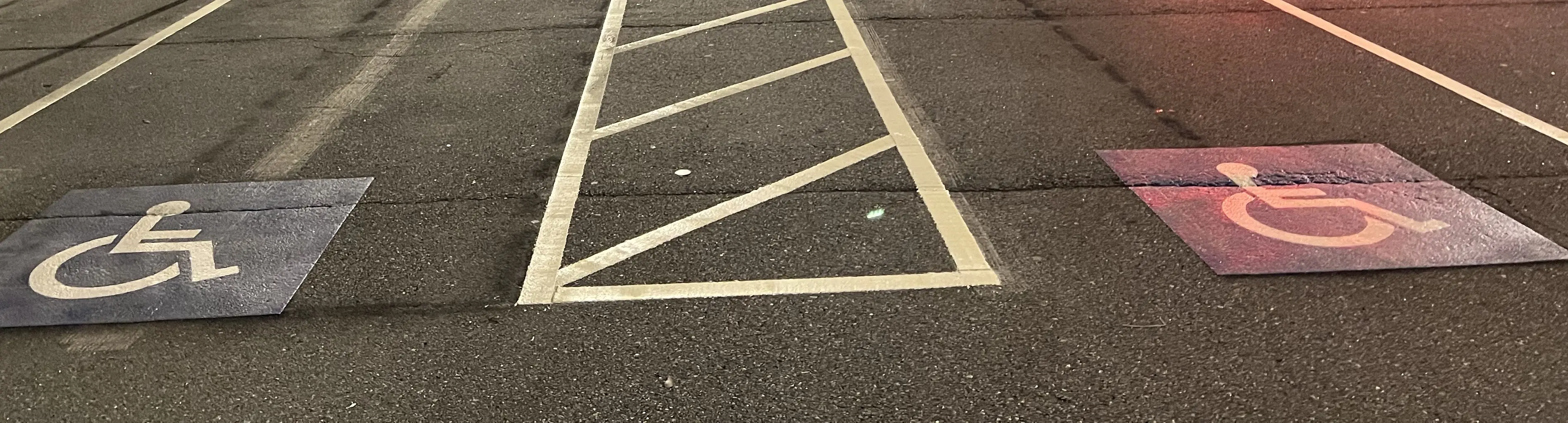 Freshly striped parking lot with a hatched access aisle and two accessible parking symbols